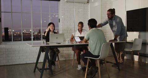 Diverse Team Collaboration in Modern Office During Evening Meeting