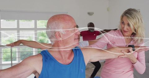 Senior man stretching with trainer guiding posture in bright fitness studio active aging