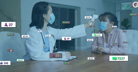 Clinician measuring patient temperature with infrared thermometer while recording vitals