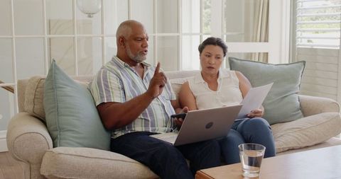 Senior Couple Reviewing Retirement Documents, Using Laptop in Living Room