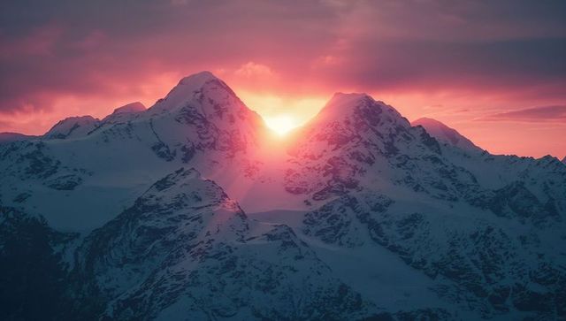 Sun rising over snowy alpine peaks at dawn