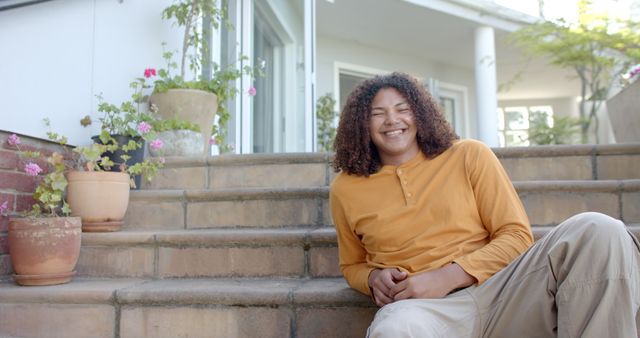 Smiling Young Man Sitting on Porch Steps with Potted Plants - Download Free Stock Images Pikwizard.com