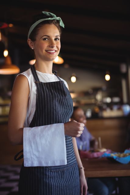 Portrait of beautiful waitress with napkin standing at restaurant