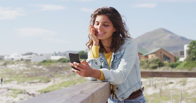 Smiling Woman Engaging with Smartphone on Scenic Beach - Download Free Stock Images Pikwizard.com