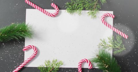 Festive christmas candy canes and greenery with blank paper
