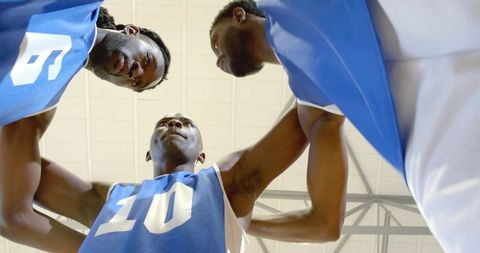 African american basketball teammates stacking hands in energetic pre-game huddle