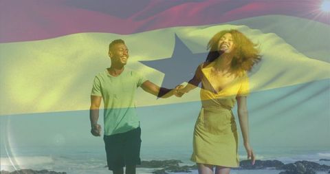 Couple walking hand-in-hand on rocky beach under waving star flag overlay laughing in sunlight