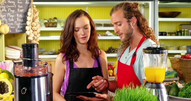 Workers discussing over digital tablet at juice counter in organic market