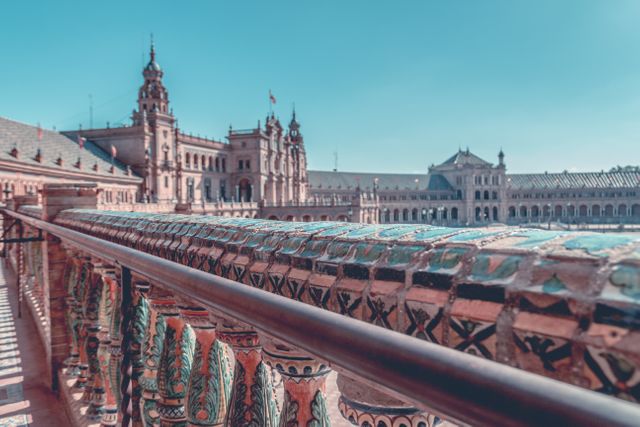 Showcasing the elaborate architectural features of Plaza de España in Seville with its ornate ceramic balustrade and prominent historical buildings in the background. Ideal for illustrating travel destinations, Spanish culture, historic landmarks, heritage tourism, and architectural beauty.