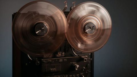 Spinning vintage reel-to-reel tape recorder with amber reels and metal knobs