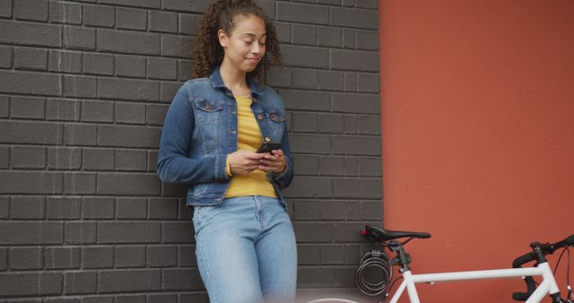 Young Woman Leaning on Wall Using Smartphone Next to Bicycle - Download Free Stock Images Pikwizard.com