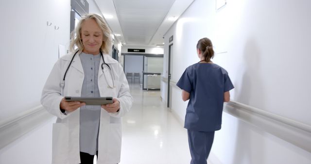 Female Doctor Smiling While Using Tablet in Hospital Corridor - Download Free Stock Images Pikwizard.com