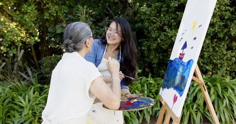 Mother and Daughter Painting Together in Sunny Garden