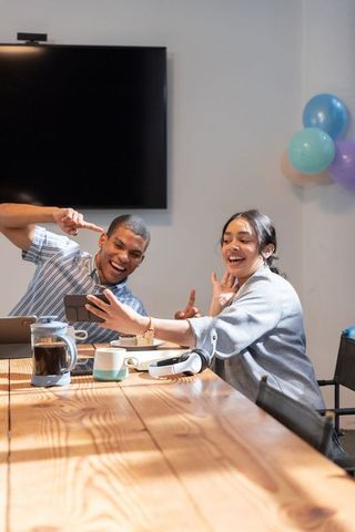 Happy Coworkers Engaging with Smartphone During Meeting