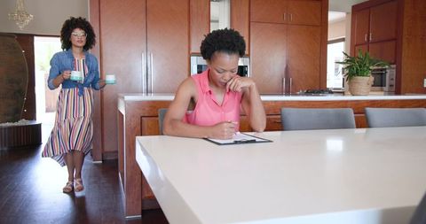 Two women discussing documents over coffee in spacious kitchen
