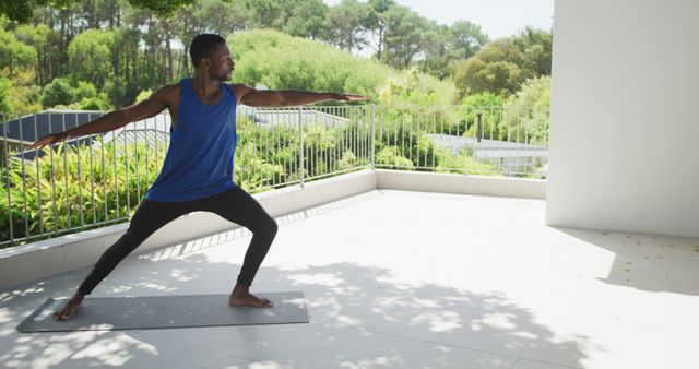 African american man practicing yoga exercising on sunny garden terrace. staying at home in isolation during quarantine lockdown.