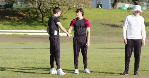 Diverse teammates shaking hands on sports field