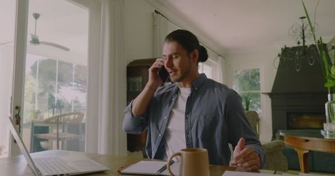 Man Talking on Smartphone Working Remotely in Home Office