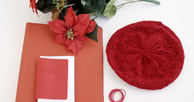 This image shows various travel essentials including a red passport, a red notebook, a red beret, rubber bands, and flowers. Ideal for travel blogs, packing guides, and holiday preparation articles, this photo highlights the importance of organizing travel essentials with a stylish red theme.
