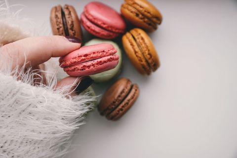 Colorful macarons and hand with cozy sweater displaying treats