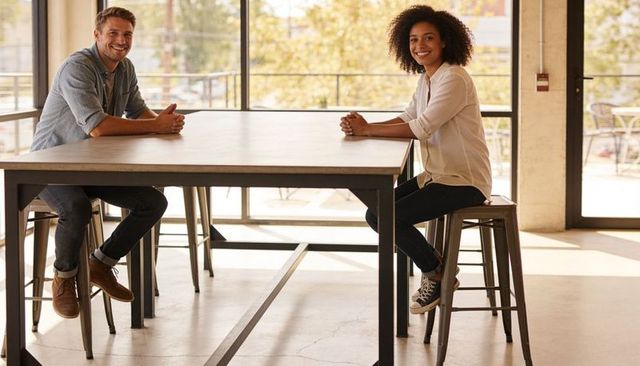 White man and woman collaborating at modern coworking table in sunlit industrial loft