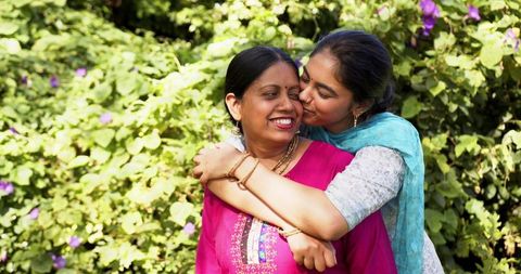 Daughter hugging mother affectionately in sunny garden