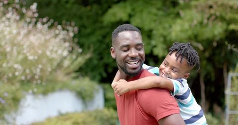 African American Father Giving Piggyback Ride Son Outdoors