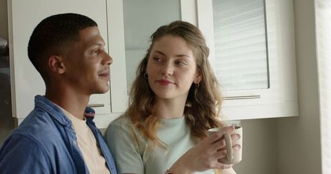 Young couple sharing cozy morning in minimalist kitchen holding ceramic coffee mug