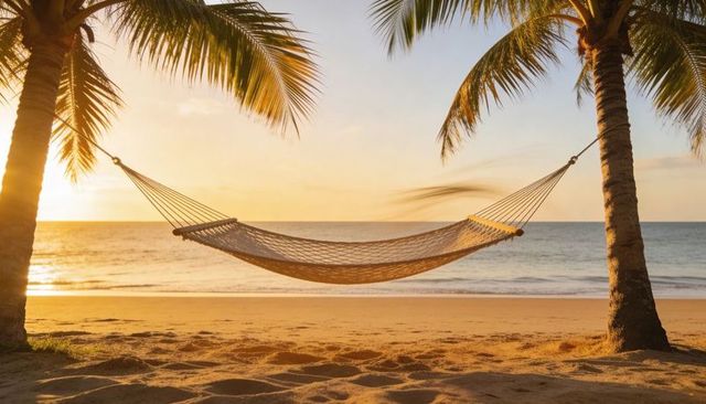 Woven hammock swaying between palm trees at golden sunset on tropical beach, ocean horizon