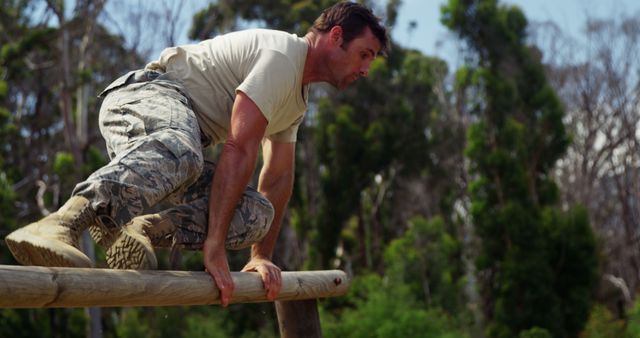 Caucasian man climbs over a wooden obstacle outdoors - Download Free Stock Photos Pikwizard.com