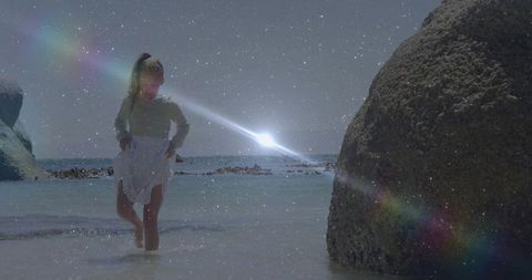 Child Walking Through Shallow Seawater with Lens Flare at Rocky Beach