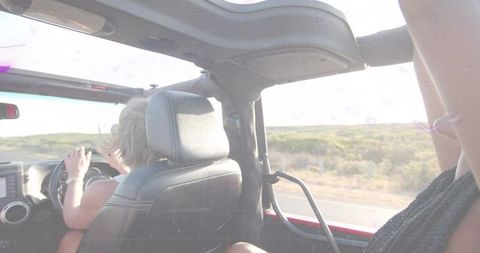Friends Enjoying Road Trip in Red Convertible on Scenic Highway
