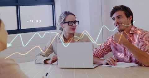 Colleagues discussing analytics over laptop with colorful line chart overlays