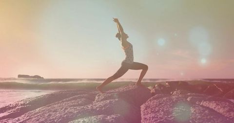 Sunset yoga warrior pose on rocky shoreline practicing mindfulness and outdoor wellness