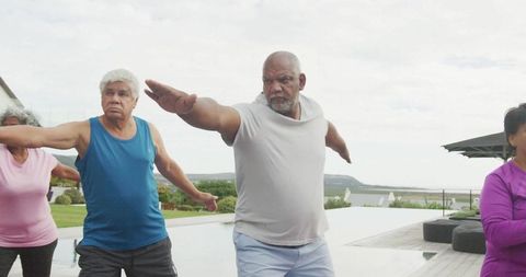 Diverse Seniors Practicing Yoga Outdoors by Infinity Pool