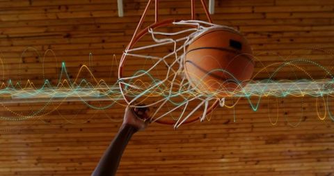 Gripping rim slam-dunking basketball passing through net with energy wave overlay
