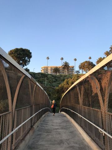 Walking on pedestrian bridge with scenic view of architecture and palm trees
