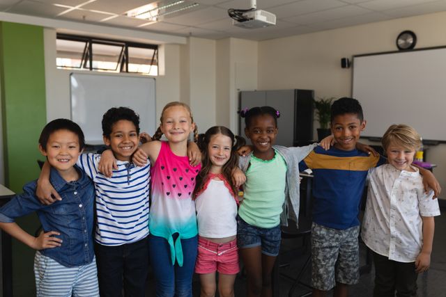 This image shows a diverse group of happy school kids standing together in a classroom, smiling at the camera. It can be used for educational materials, school brochures, advertisements promoting diversity and inclusion, and articles about childhood education and friendship.