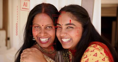 Smiling indian mother and daughter embracing in sarees with sindoor bindi and jewelry