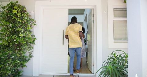 Friends entering home carrying flowers and gifts