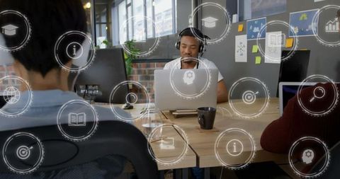 Focused man wearing headphones working on laptop in open office with collaboration hud