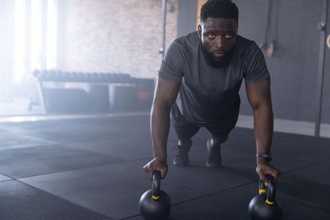African american man performing kettlebell pushup, intense focus in industrial gym