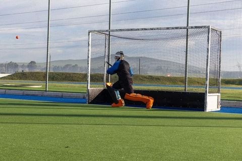 Field Hockey Goalkeeper Blocking Ball in Intense Game