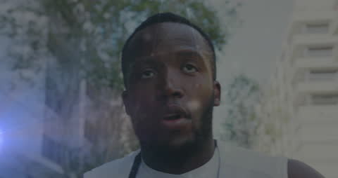 Focused Male Athlete with Headphones Running in Urban Environment