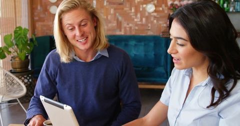 Two Professionals Collaborating with Tablet in Cozy Lounge Environment