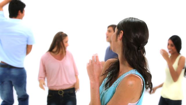 A group of young adults enjoying a lively moment together, with one focal brunette seen turning with a smile. Captures the essence of joy and friendship, with cool and casual outfits reflecting a relaxed atmosphere. Ideal for concepts related to socializing, community events, happiness, and youthful lifestyle.