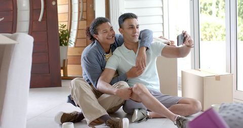 Happy Gay Couple Taking Selfie During House Move