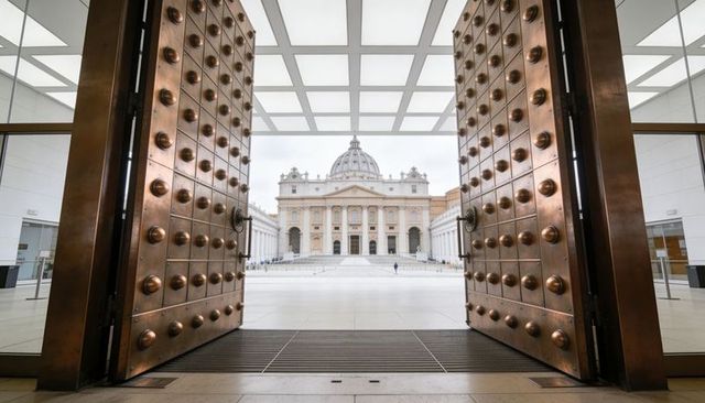 Bronze studded doors framing st peter's basilica dome and expansive vatican plaza, symmetry