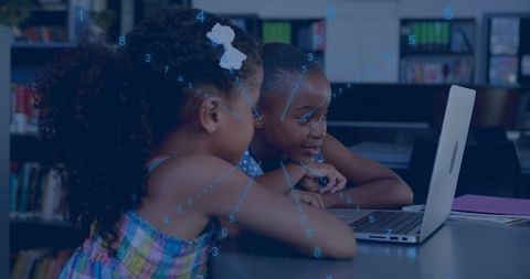 Girls collaborating on laptop in library studying STEM learning and digital teamwork skills