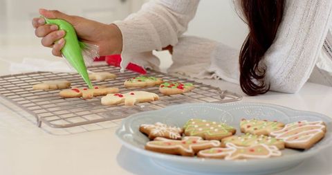 Mid Adult Woman Decorating Holiday Sugar Cookies in Kitchen
